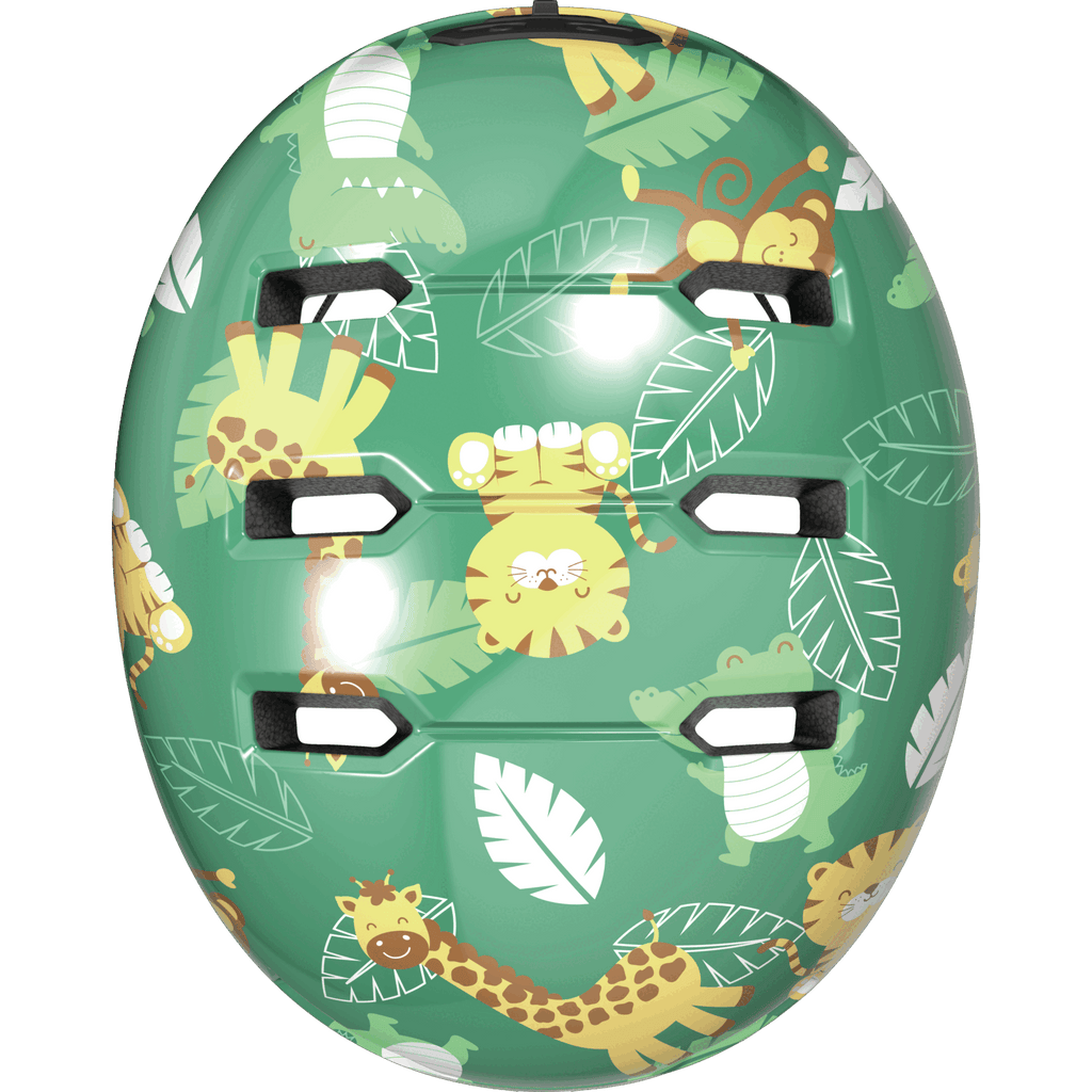 Der Abus - Skurb Kid von Abus ist ein grüner Helm im Skater-Stil für Kinder, mit Cartoon-Löwen, Giraffen, Affen, Krokodilen zwischen großen Blättern und mehreren Belüftungsschlitzen oben.