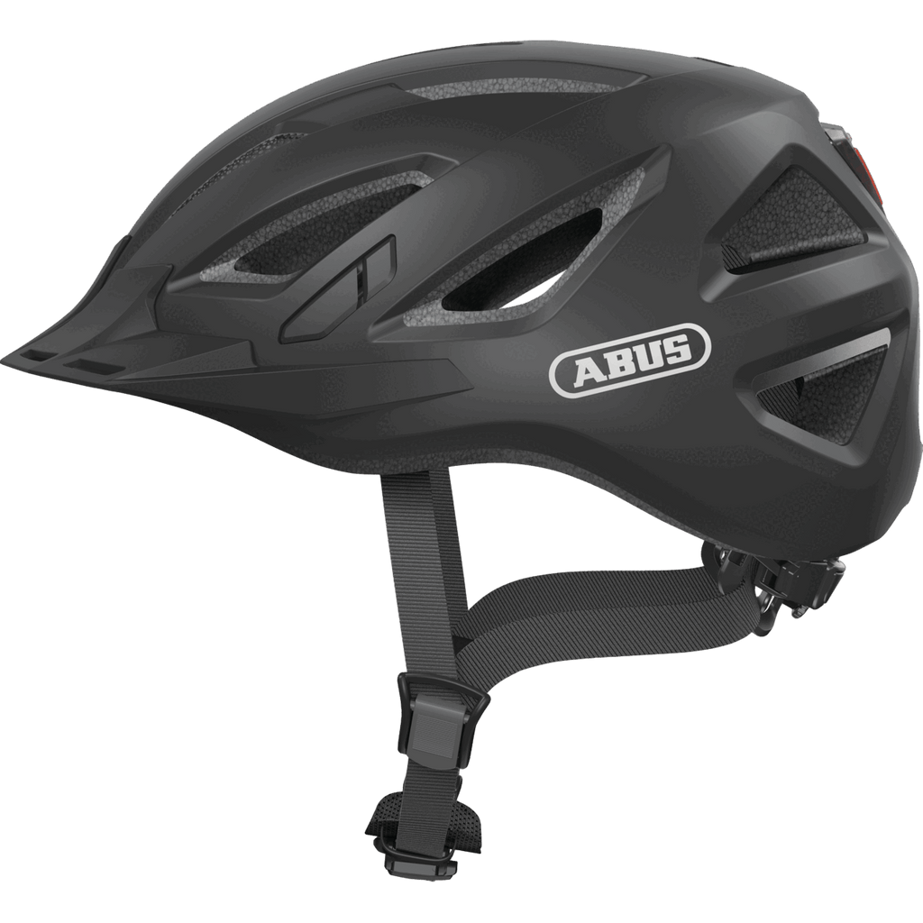 Der Abus - Urban-I 3.0 Helm in Schwarz verfügt über Belüftungslöcher, verstellbare Riemen, einen Magnetverschluss und eine matte Oberfläche, die von der Seite vor einem einfarbigen Hintergrund gezeigt wird.