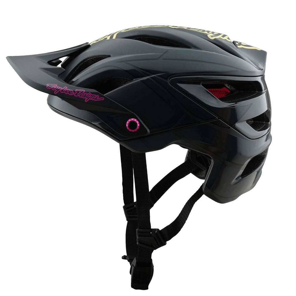 Der Troy Lee Designs A3 Helm ist ein schwarzer MTB-Helm mit Magnajust®-Visier, Kinnschutz, pinkem und gelbem Troy Lee Designs"-Schriftzug und roten Mesh-Belüftungsöffnungen auf einem schlichten grauen Hintergrund.