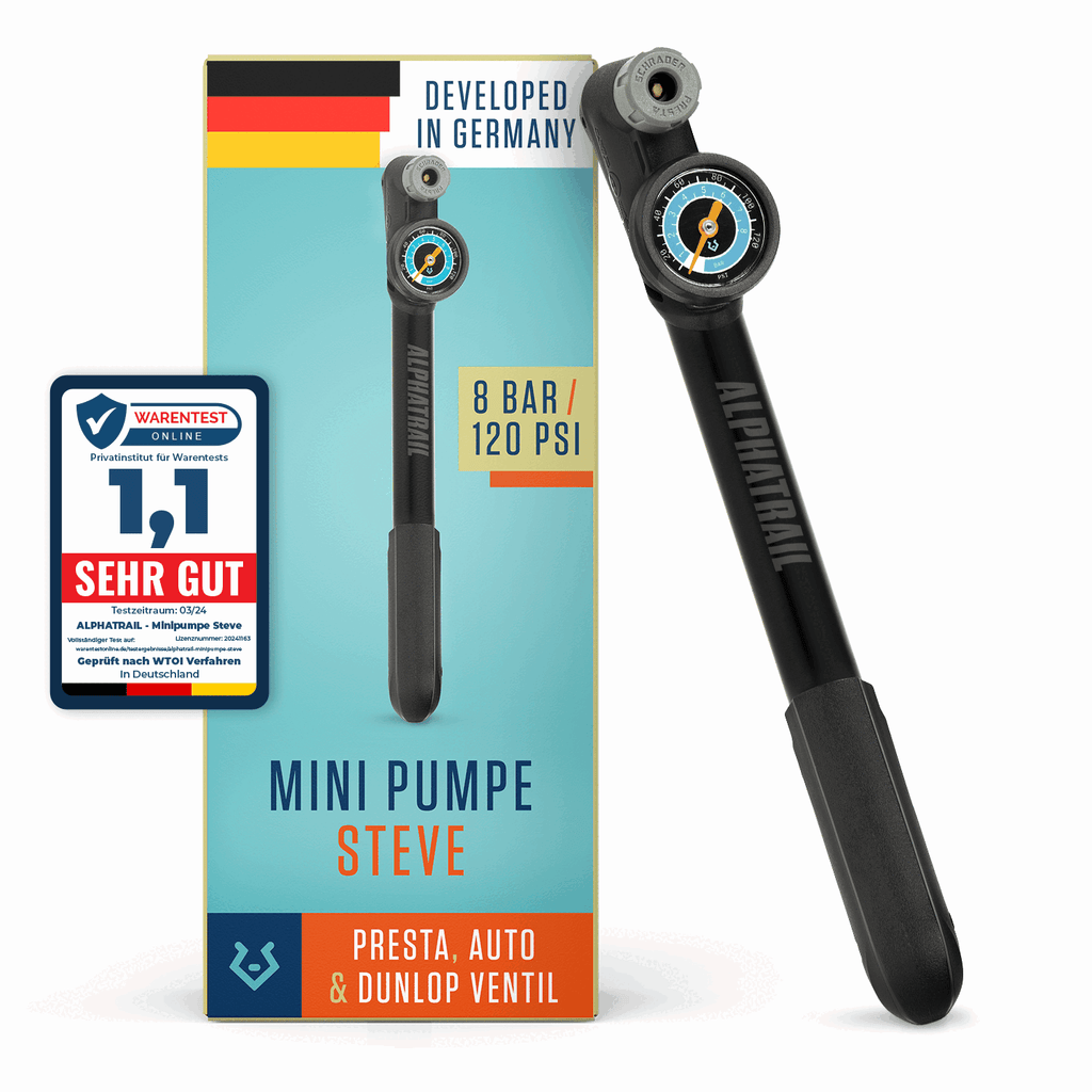 Eine schwarze Alphatrail Minipumpe Steve von Alphatrail wird neben ihrer Verpackung mit der Aufschrift "Mini Pumpe Steve" gezeigt, die mit Presta-, Auto- und Dunlop-Ventilen kompatibel ist. Ein deutsches Qualitätssiegel und ein Hinweis auf lebenslanger Garantie sind ebenfalls zu sehen.